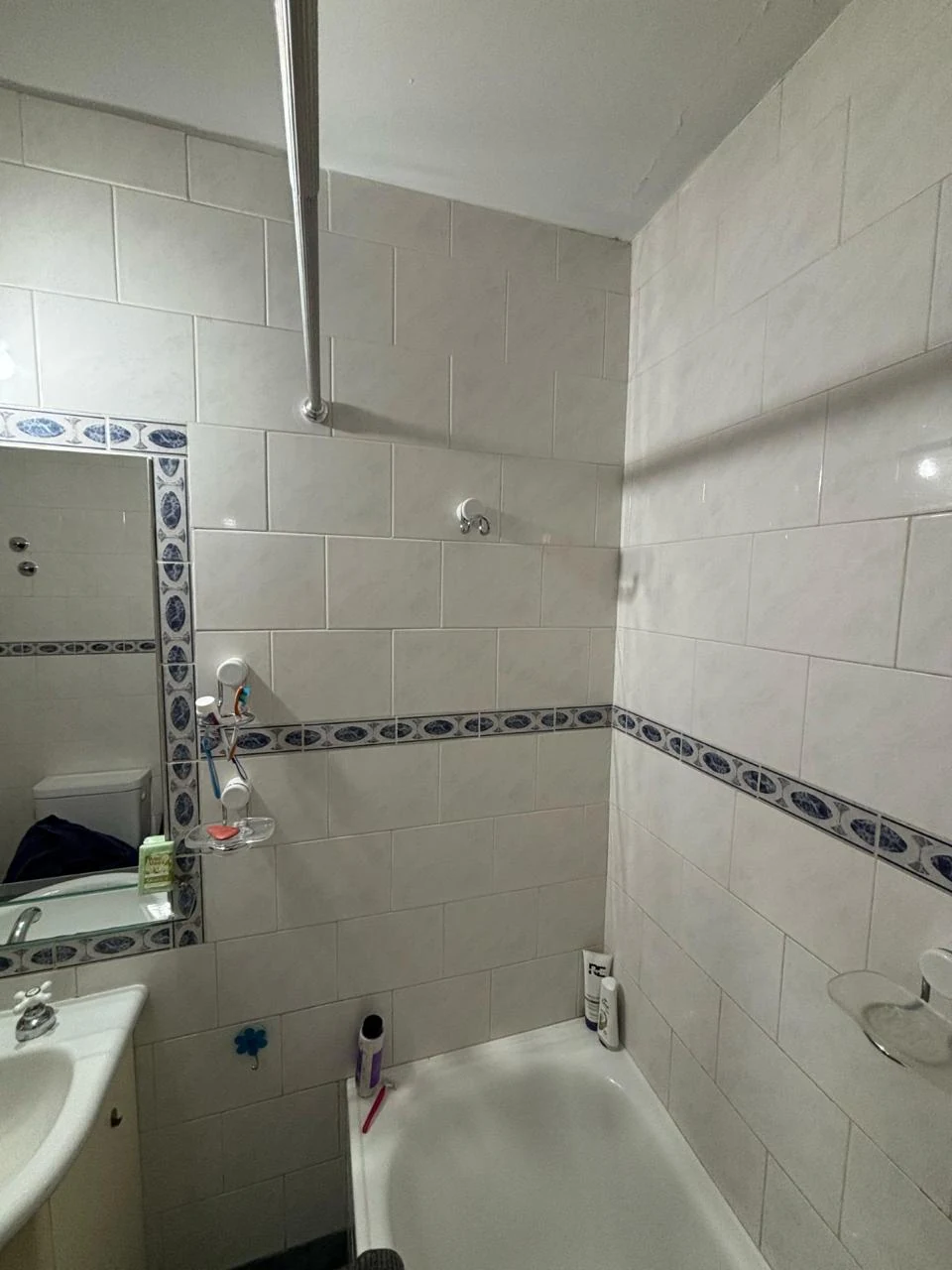 Baño antes: azulejo cerámico claro con guarda decorativa
