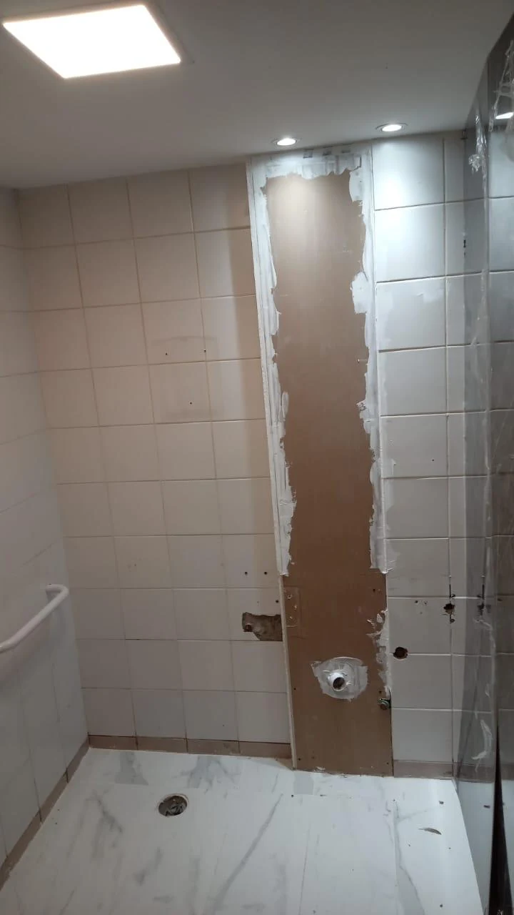 Baño antes: azulejo blanco existente, pared preparada