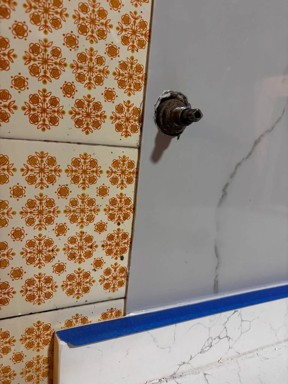 El azulejo naranja original al lado de la placa blanca nueva